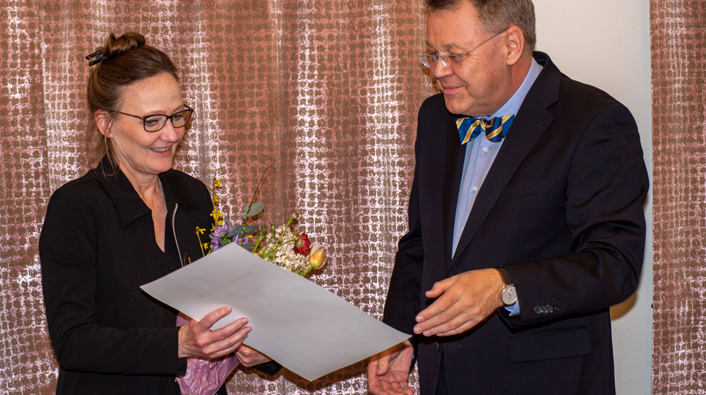 Malin receives a diploma and flowers from Peter, older man. 